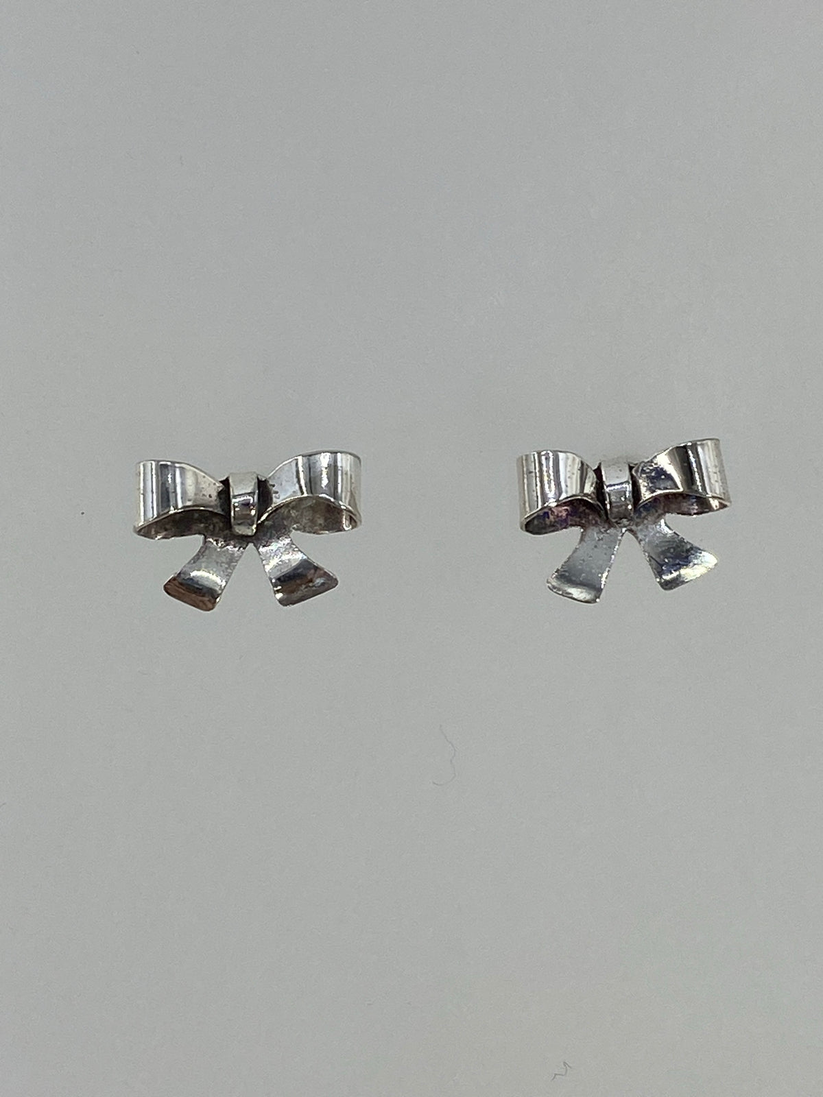 Par de aretes de plata cartoneado en forma de arco minimalista, vista frontal