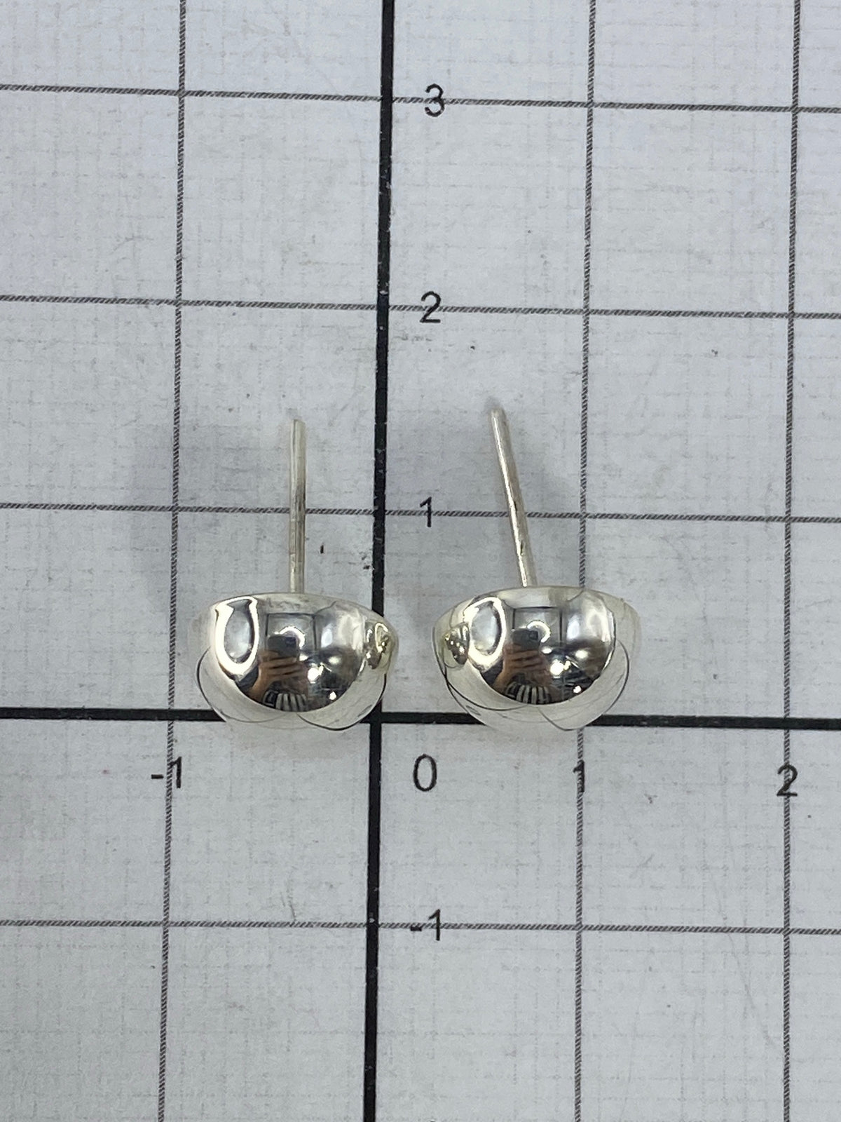 Aretes sobre fondo neutro mostrando el tamaño real (1.5 cm) y el Quinto 925