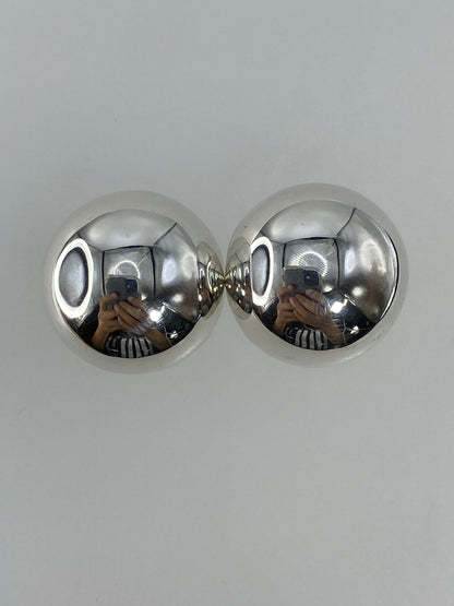 Par de aretes de plata cartoneado, esféricos y brillantes, sobre fondo blanco