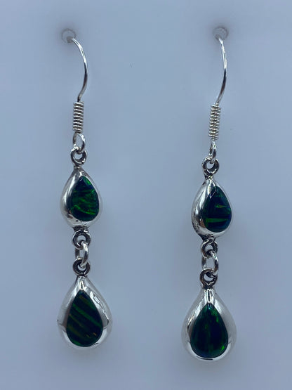 Par de aretes de plata con ópalo de fuego verde, colgando de un gancho