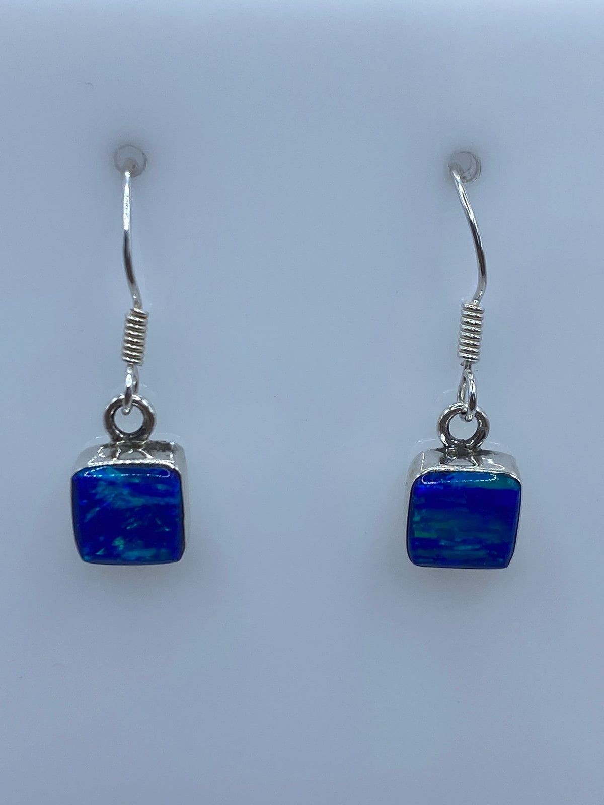 Detalle de arete individual mostrando el Ópalo de Fuego azul y el engaste a mano en plata 950