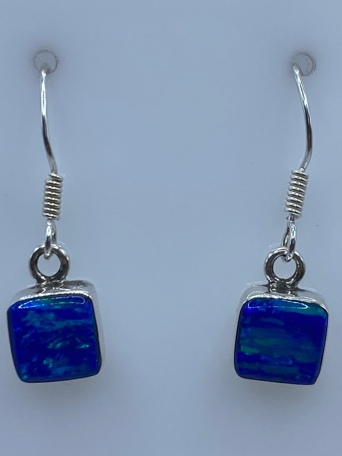 Aretes de plata Ópalo de Fuego vistos de frente, brillando con reflejos azules