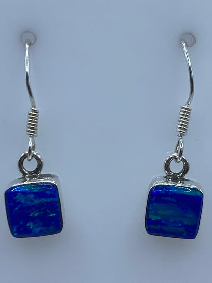 Aretes de plata Ópalo de Fuego vistos de frente, brillando con reflejos azules
