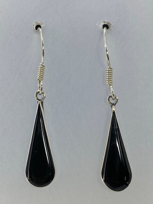 Aretes de plata 925 con onix negro de 3 cm de largo, colgando sobre fondo gris