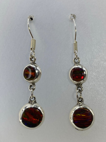 Par de aretes de plata 925 con Ópalo de Fuego rojo engastado, colgando sobre fondo blanco