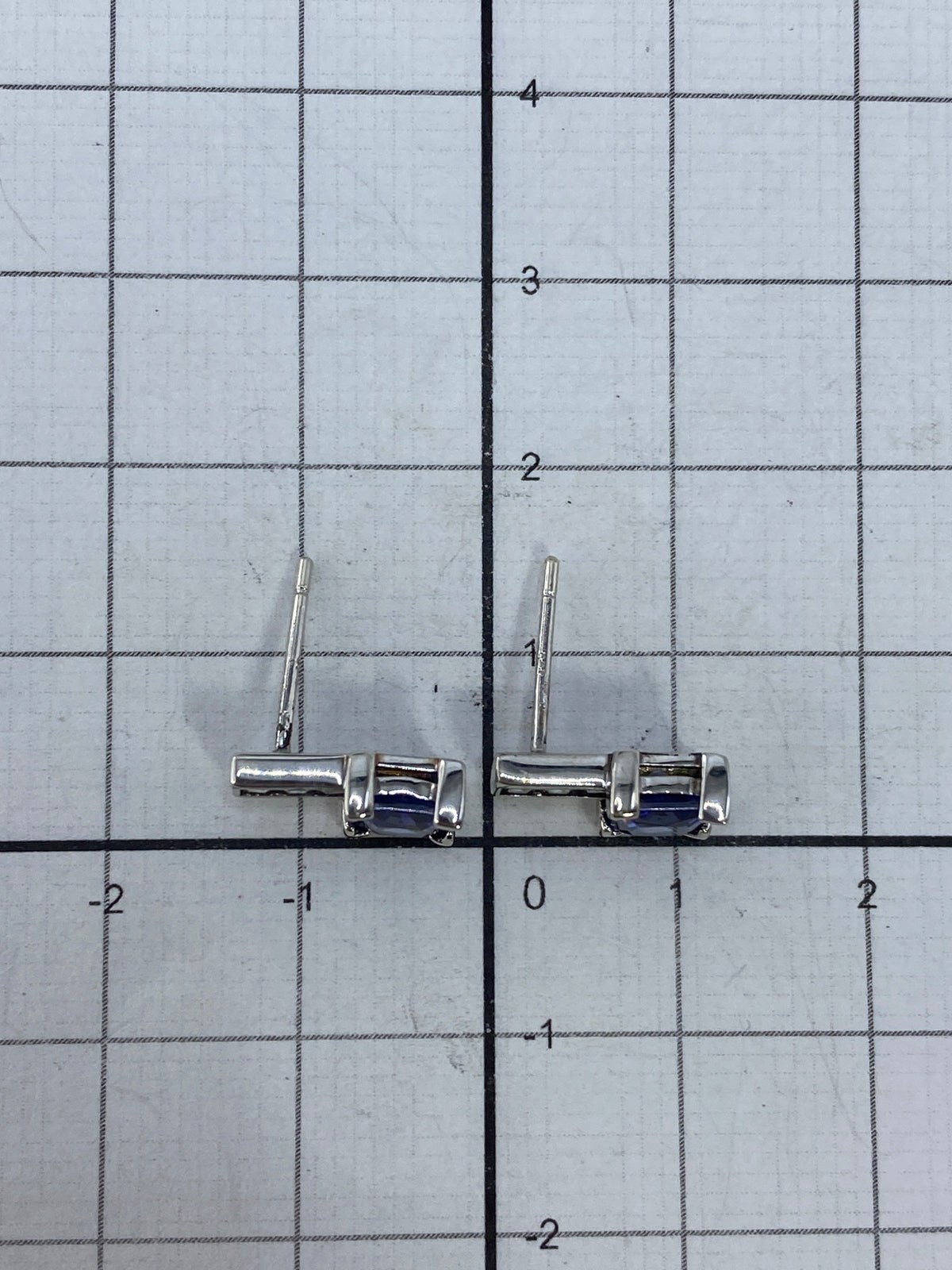 Aretes de plata sobre tela azul mostrando el reflejo de la piedra