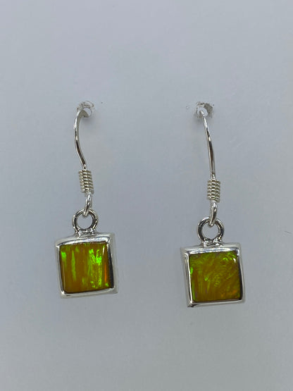 Par de aretes plata ópalo de fuego amarillo sobre fondo blanco, colgando del gancho