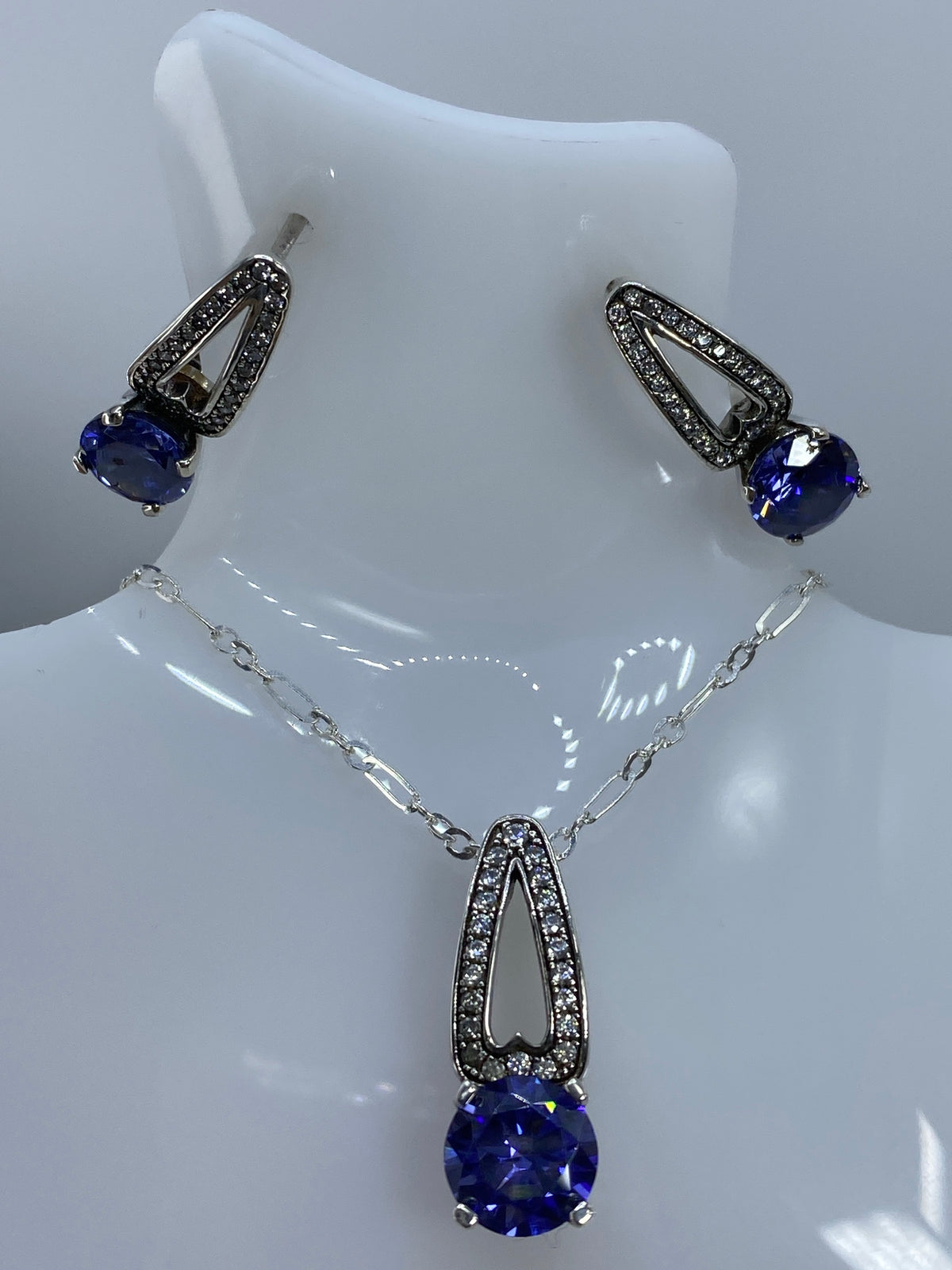 Aretes con circonia azul colgando delicadamente, mostrando el brillo de la piedra