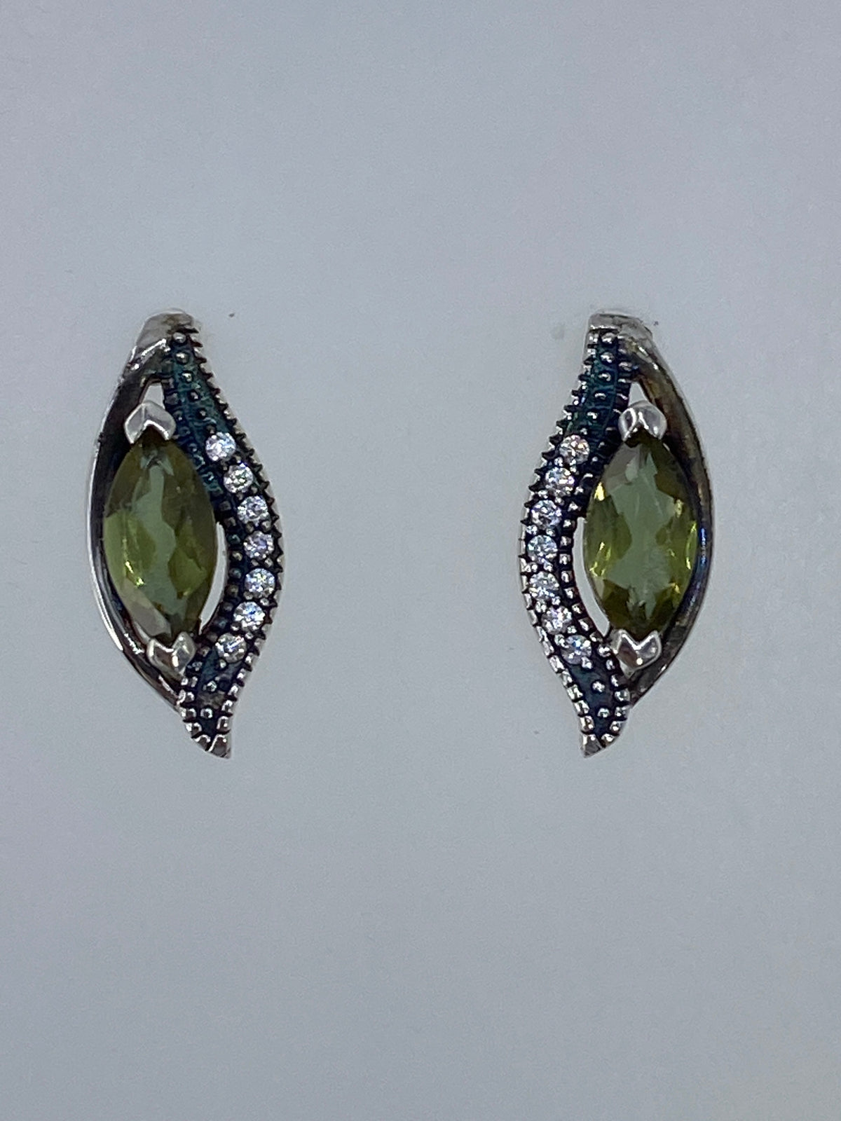 Par de aretes de plata con circonia verde olivo sobre fondo blanco