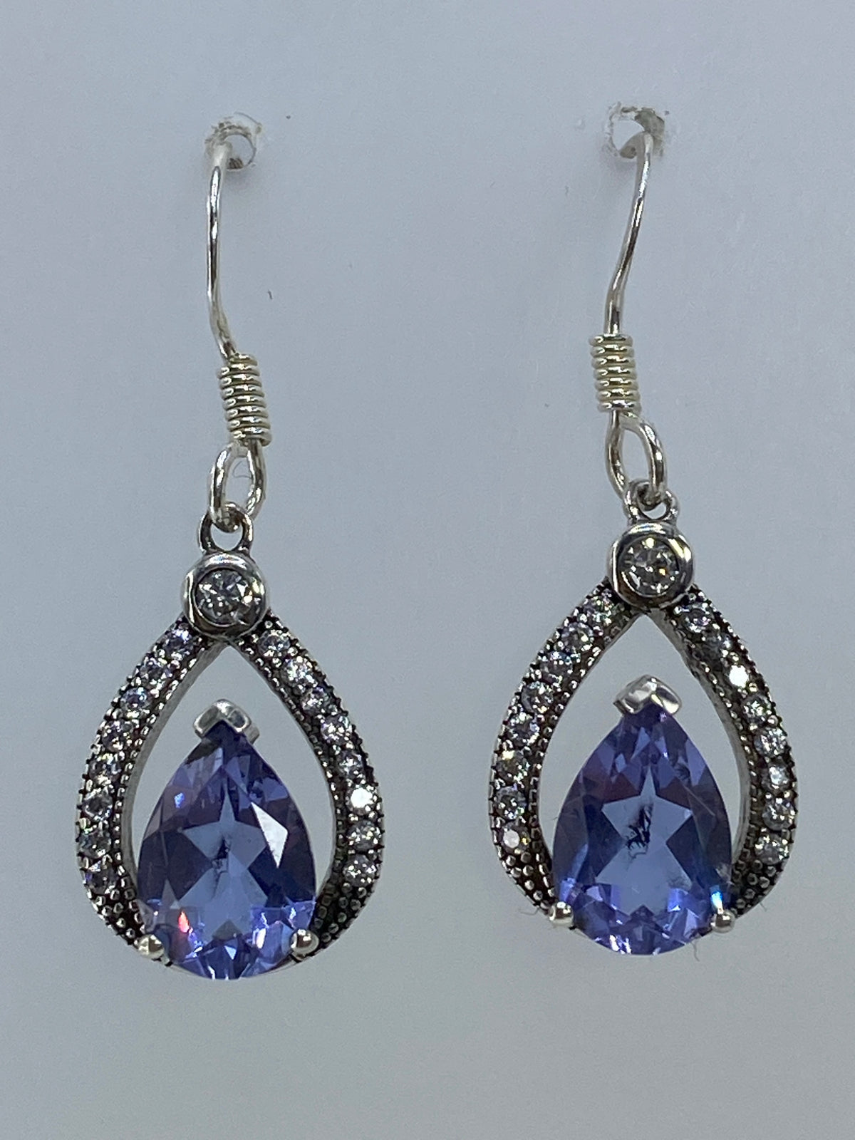 Par de aretes gota de plata 925 con circonia azul engastada, sostenidos en la mano