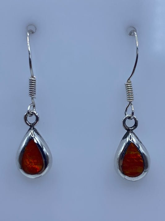 Par de aretes de plata con ópalo de fuego naranja engastado, en gancho de plata, sobre fondo azul