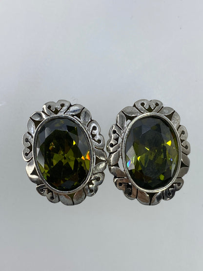 Par de aretes de plata vintage con circonia verde olivo, vista frontal simétrica sobre fondo blanco