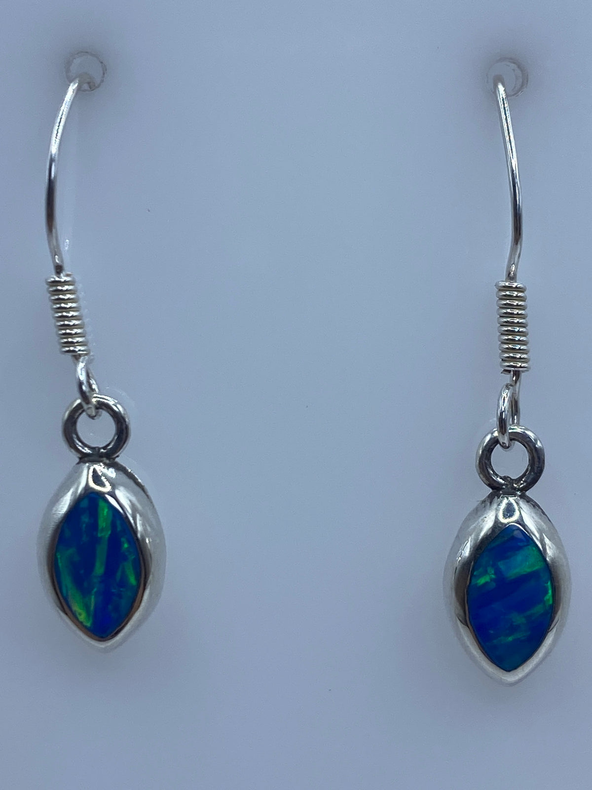 Detalle de uno de los aretes mostrando el ópalo de fuego azul engastado en plata