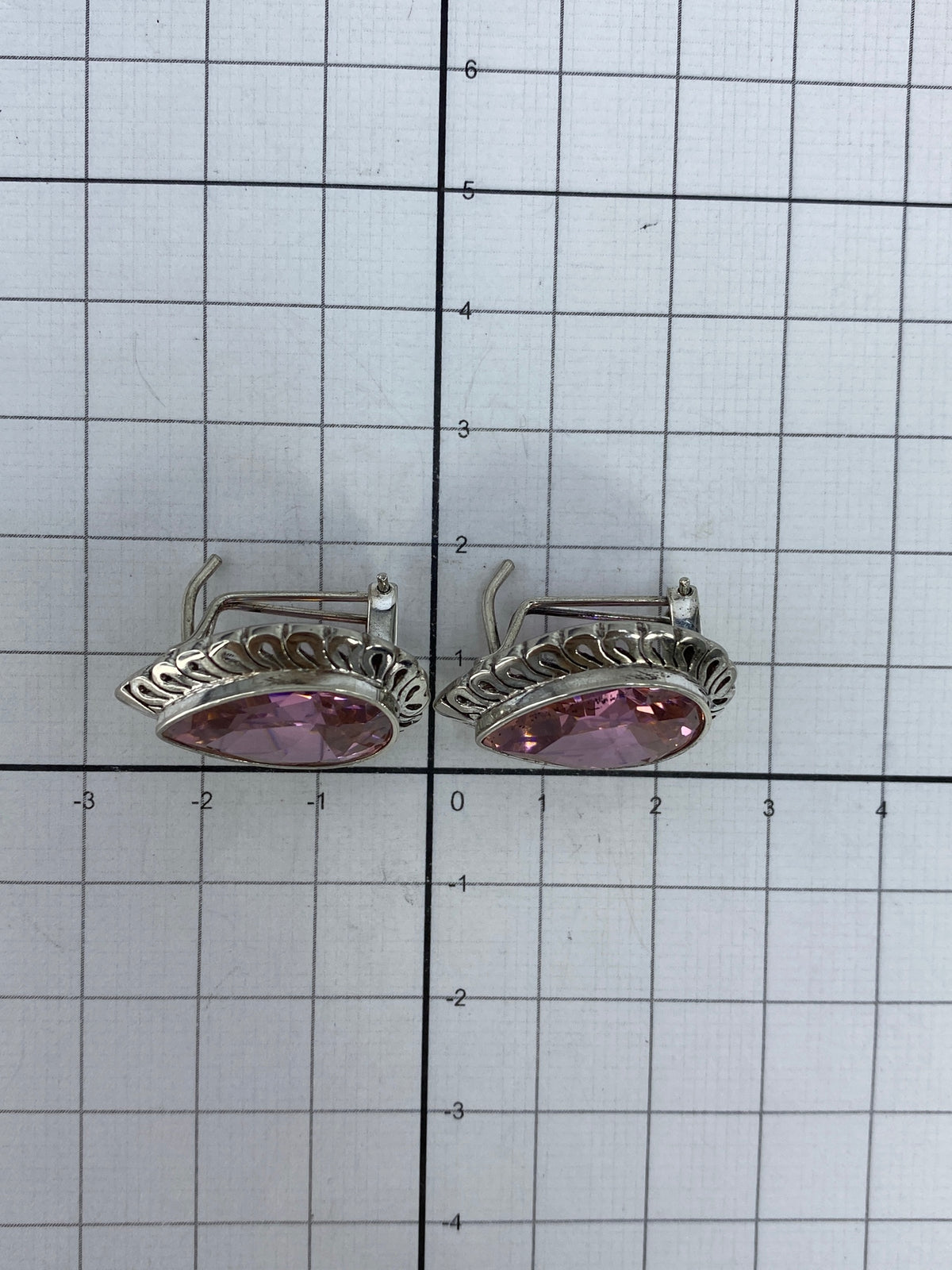 Aretes de circonia rosa en la mano, luz natural reflejando en el facetado