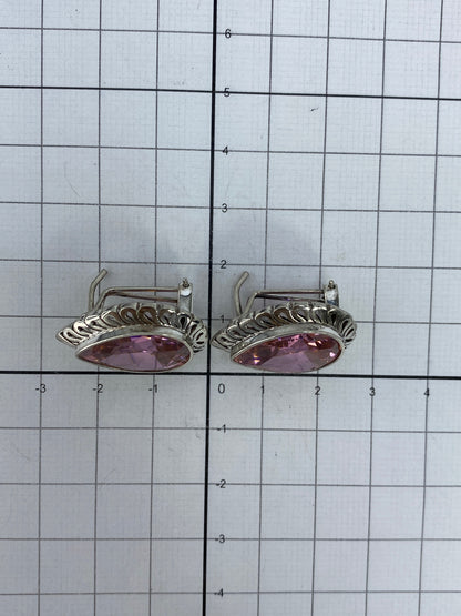 Aretes de circonia rosa en la mano, luz natural reflejando en el facetado
