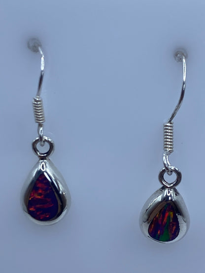 Arete de ópalo de fuego mostrando los tonos rojos y naranjas contra luz