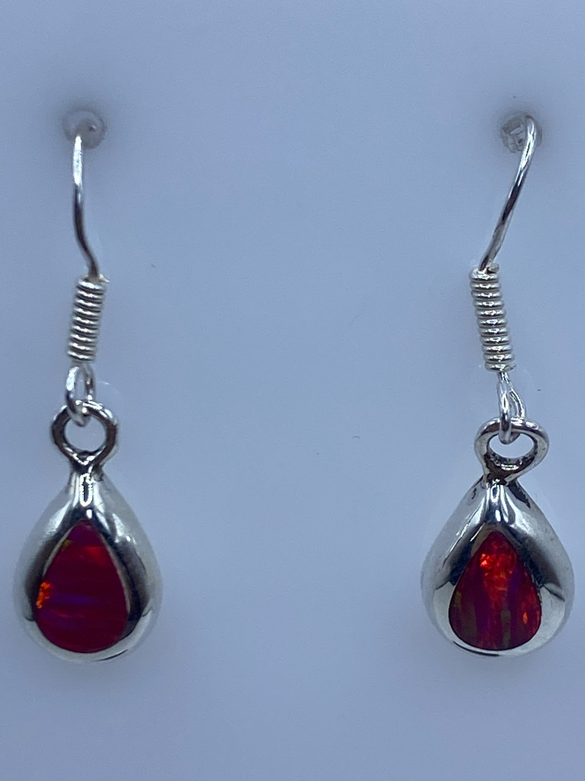 Detalle de un arete mostrando el ópalo de fuego rosa y el engaste de plata 925
