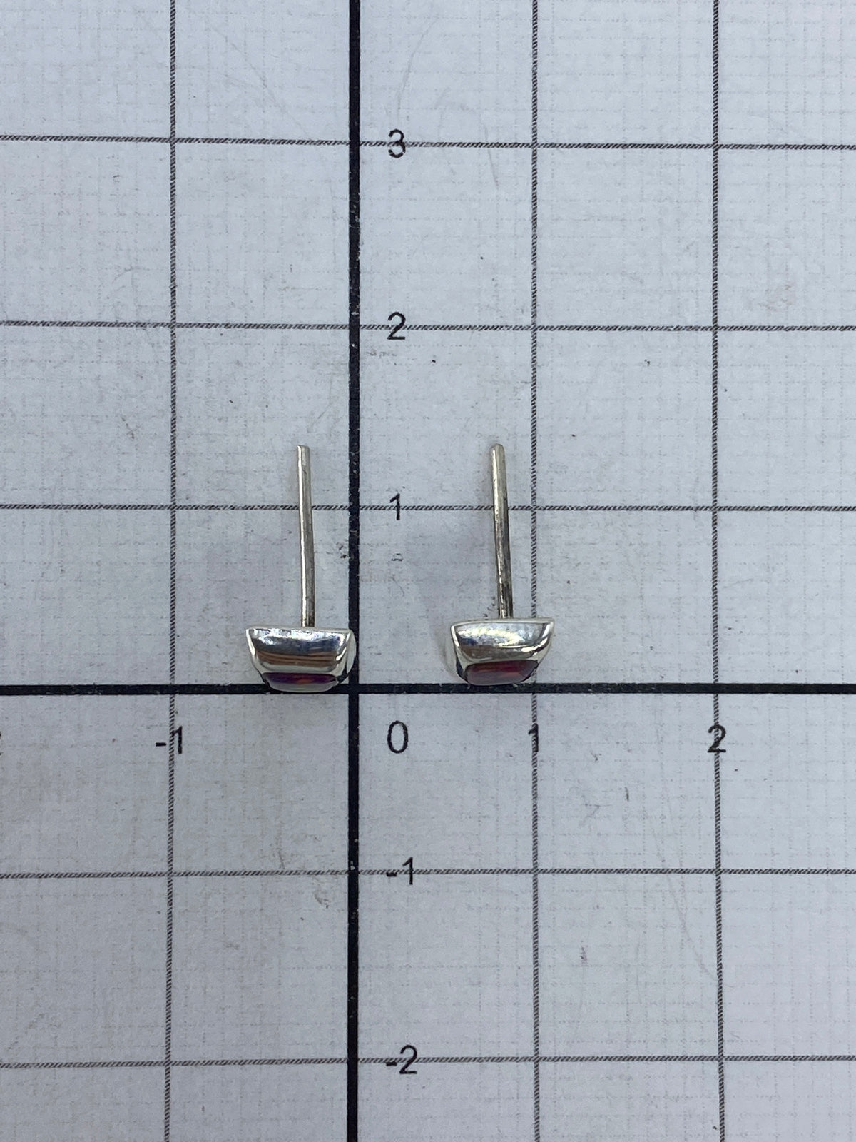 Aretes de ópalo sobre una mano, destacando el color iridiscente de la piedra