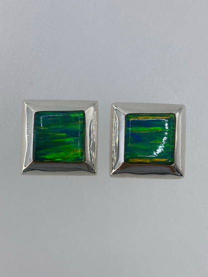 Par de aretes de plata con circonia multicolor engastada, colgando sobre fondo blanco