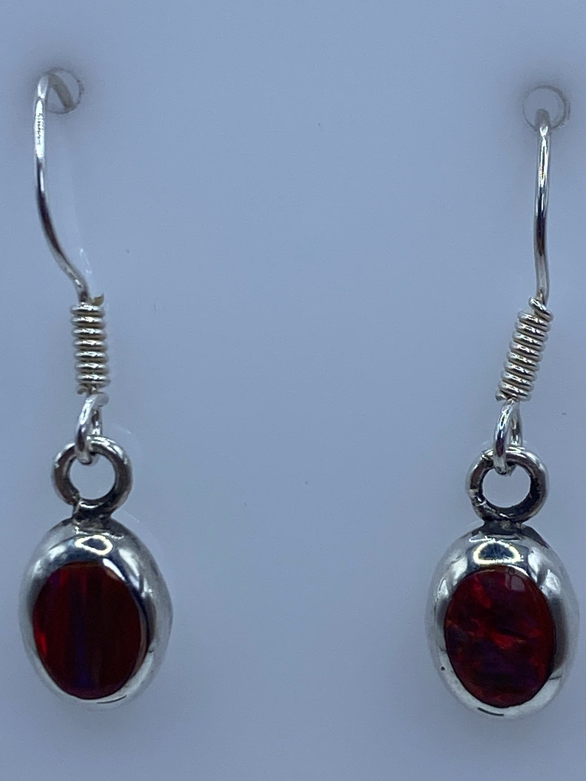 Aretes de plata con ópalo de fuego sobre escala de centímetros, mostrando largo de 2.7 cm