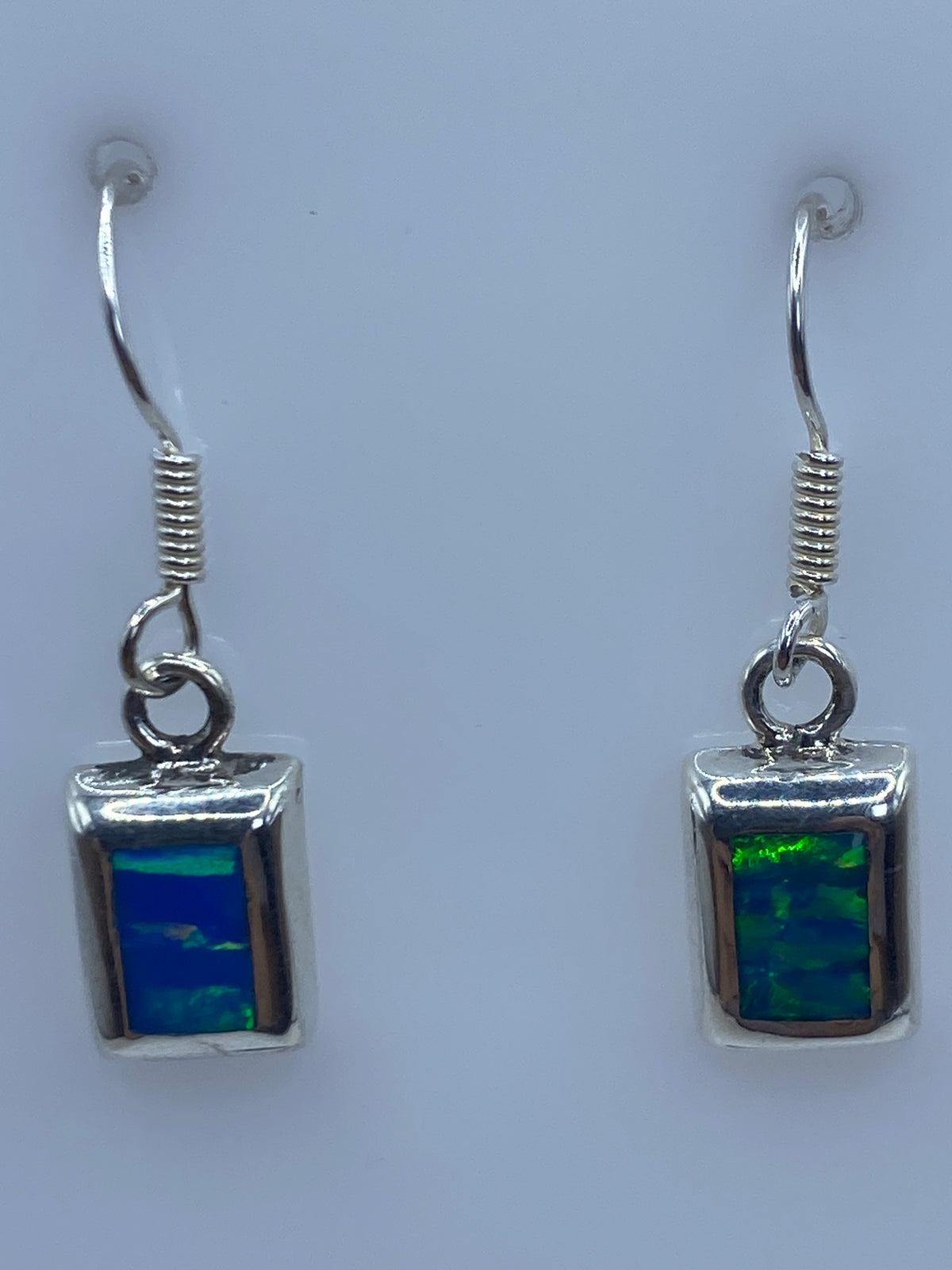 Detalle de gancho de plata y piedra de ópalo azul en uno de los aretes