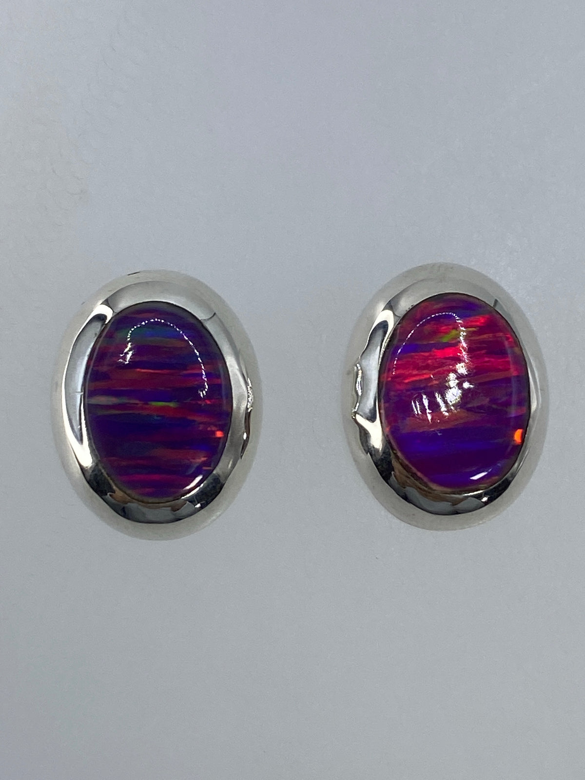 Par de aretes de plata 925 con ópalo de fuego multicolor, vistos de frente mostrando el color iridiscente