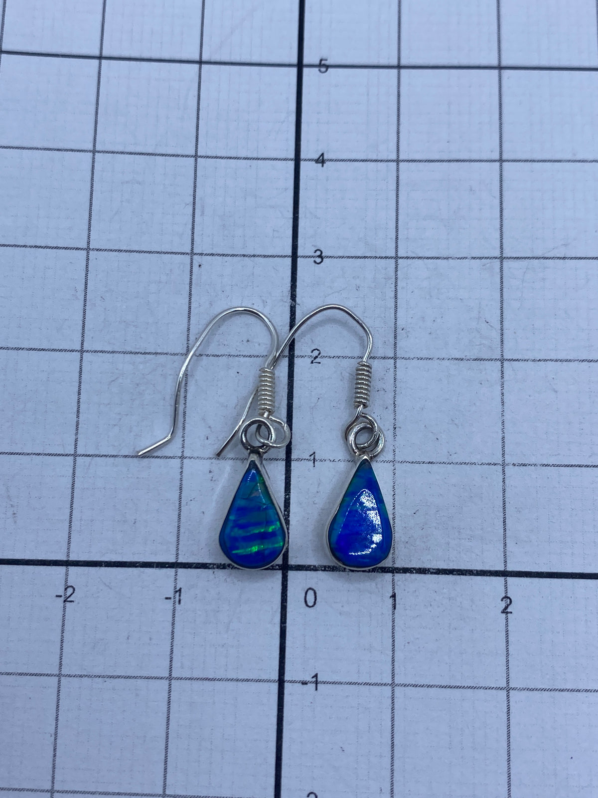 Aretes de plata pura con brillo del ópalo bajo luz natural