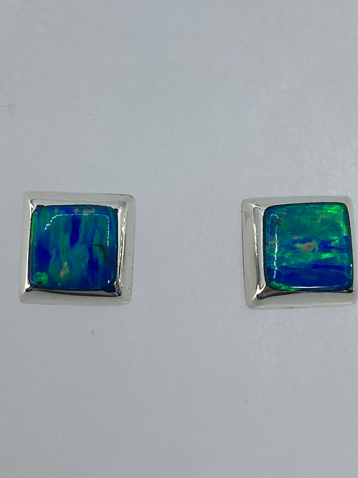 Detalle frontal de los aretes mostrando el brillo y color del ópalo de fuego