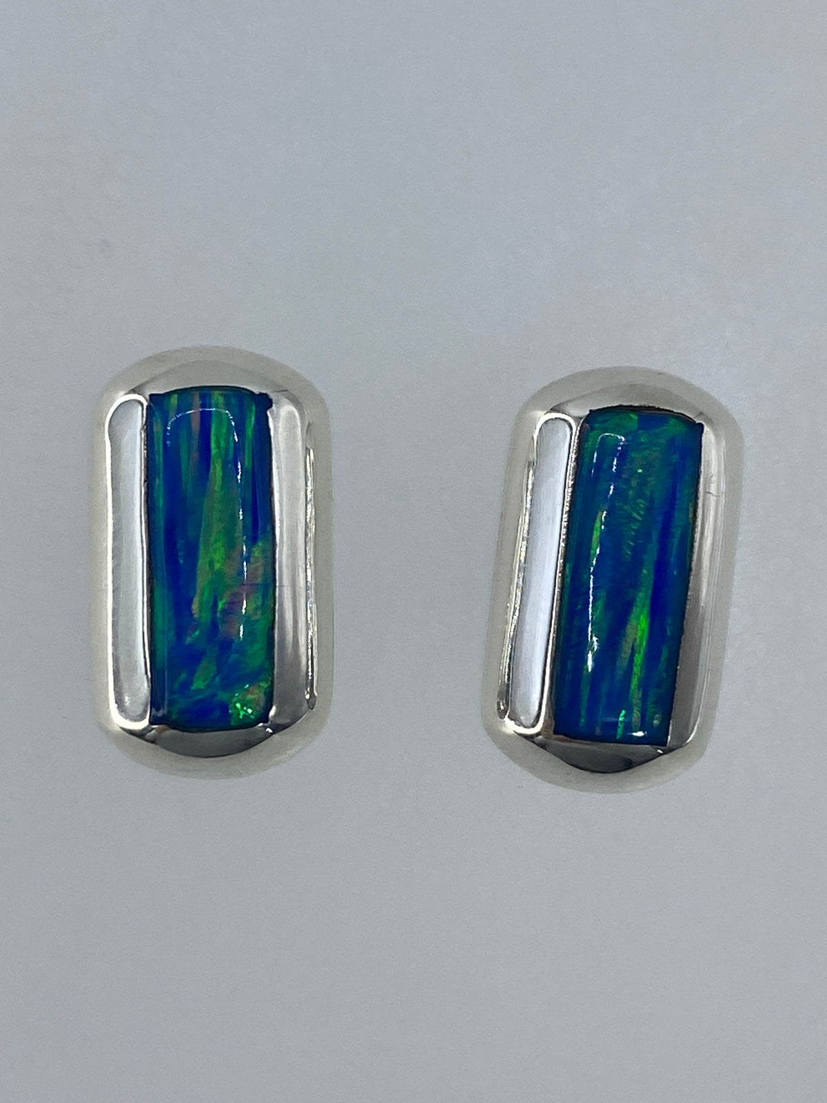 Aretes pequeños de ópalo verde limón vistos de frente, mostrando los destellos interiores