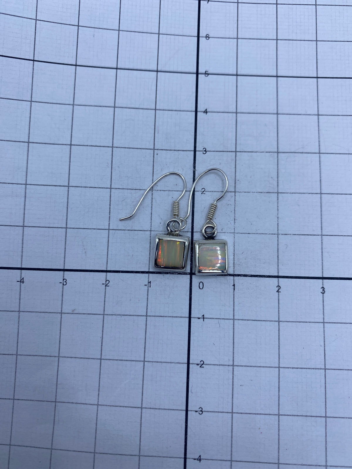 Aretes en la mano mostrando el tamaño compacto de 2.4 cm