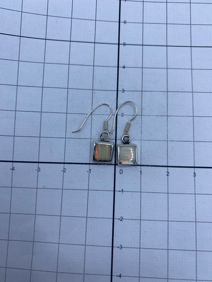 Aretes en la mano mostrando el tamaño compacto de 2.4 cm