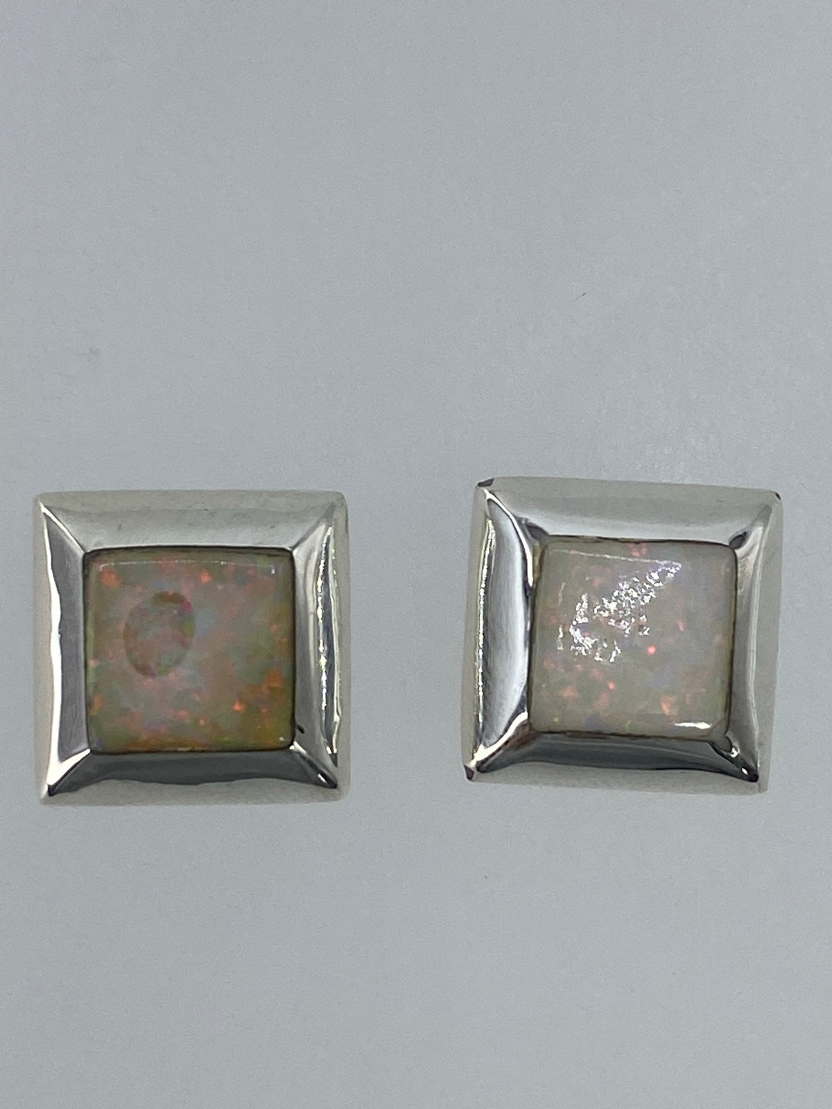 Aretes puestos mostrando el brillo y los tonos naranja y rojo del Ópalo de Fuego