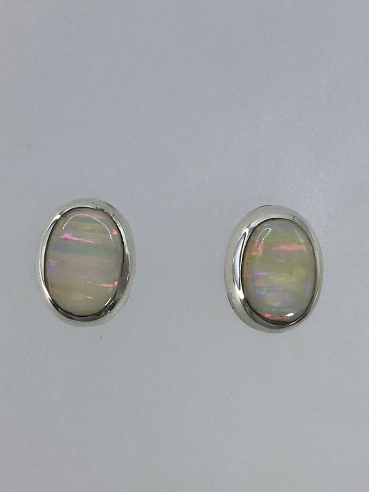Par de aretes de plata con ópalo de fuego multicolor engastados a mano, mostrando reflejos rojo, naranja y azul