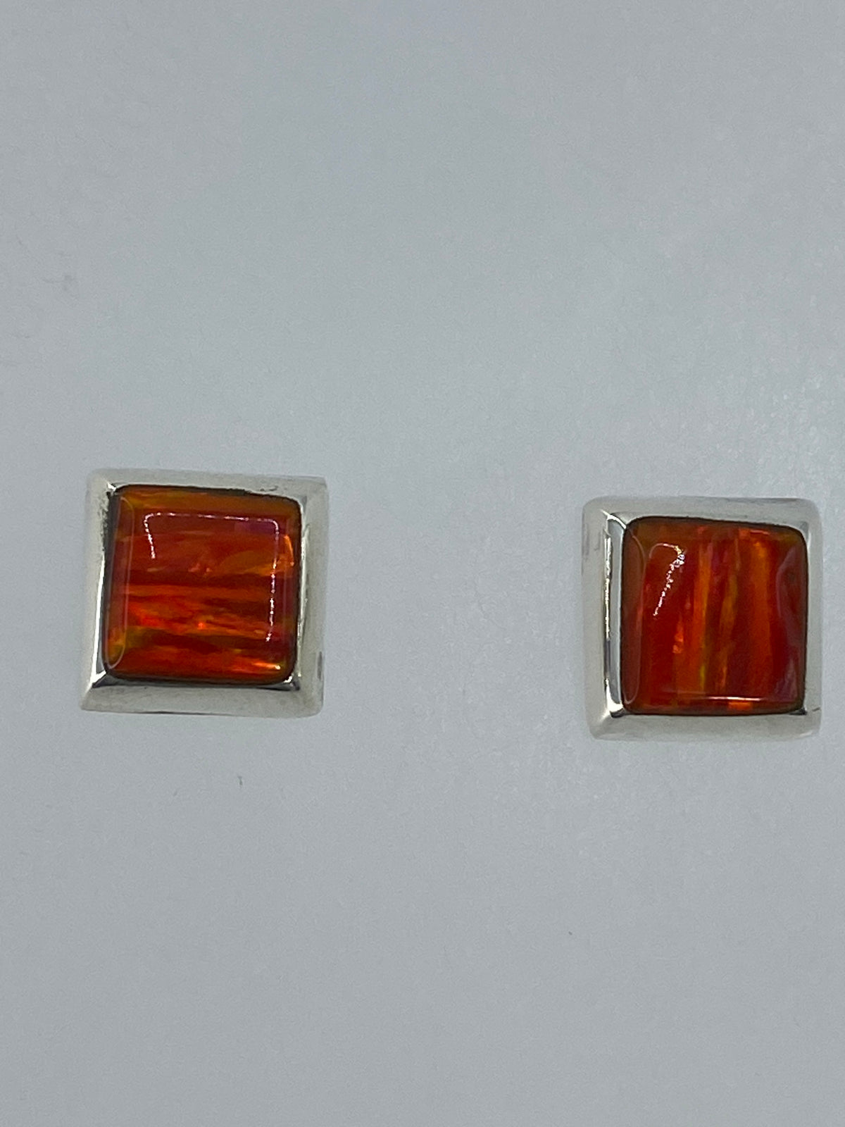 Detalle frontal de los aretes mostrando el brillo cálido del Ópalo de Fuego