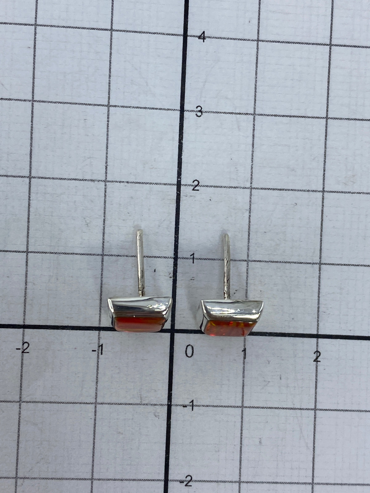 Los aretes sobre regla de medida, confirmando el tamaño de 1.3 cm, con marca del Quinto 925 visible