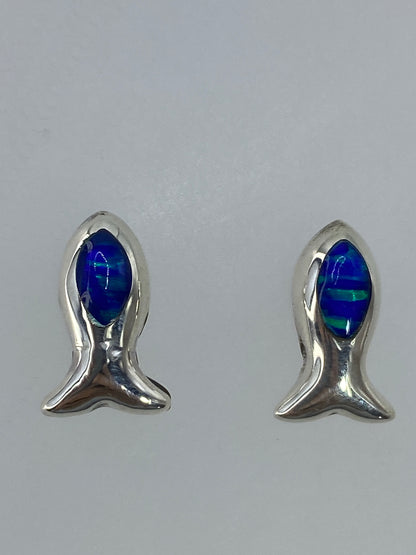 Aretes de plata sobre fondo blanco mostrando los destellos del ópalo