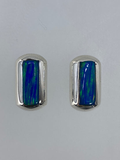 Aretes en ópalo de fuego sobre fondo blanco mostrando el reflejo multicolor