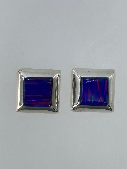 Par de aretes de plata con ópalo de fuego multicolor, vista frontal, sobre fondo gris