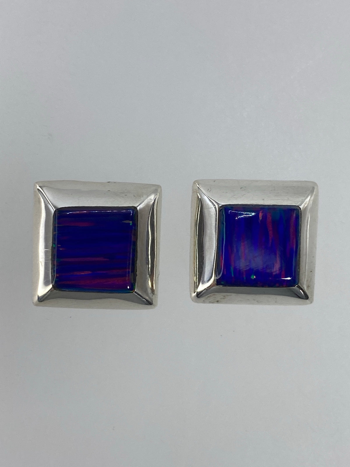 Aretes de plata engastados a mano, detalle del ópalo de fuego con destellos naranja y rojo