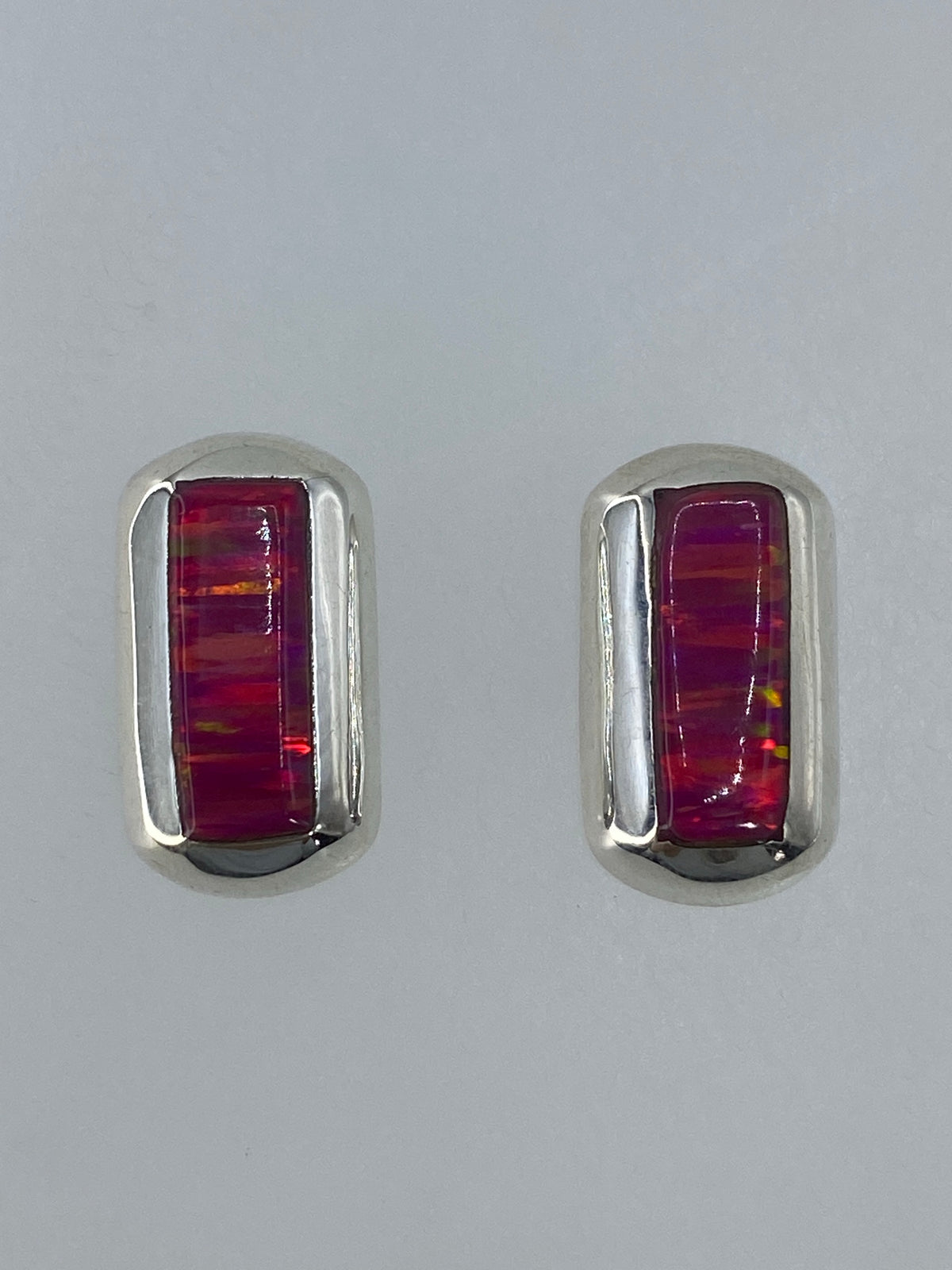 Detalle de los aretes mostrando el fuego del ópalo: tonos ámbar, rojo y verde