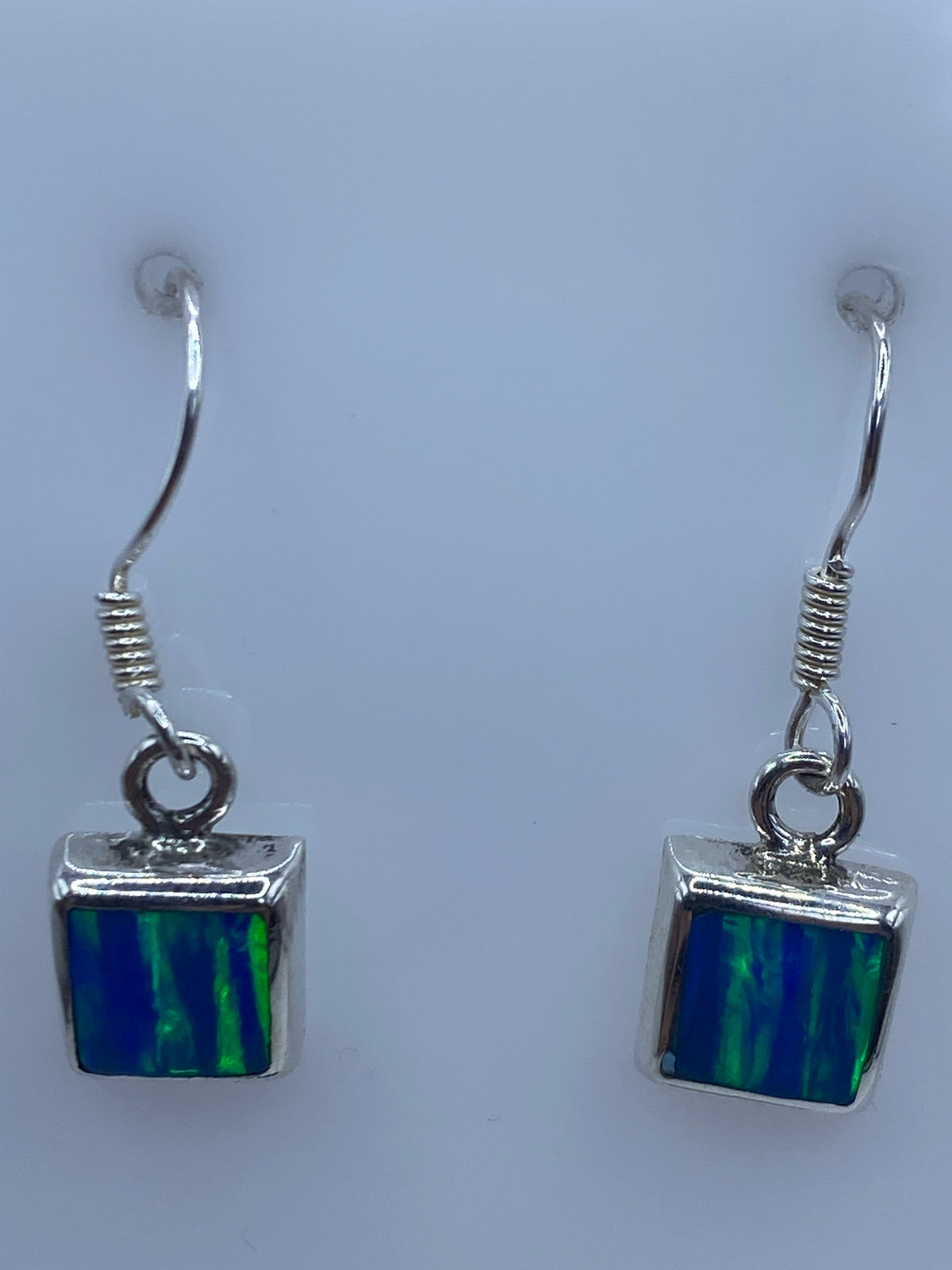 Detalle de un arete mostrando el engaste a mano de la piedra de ópalo en plata