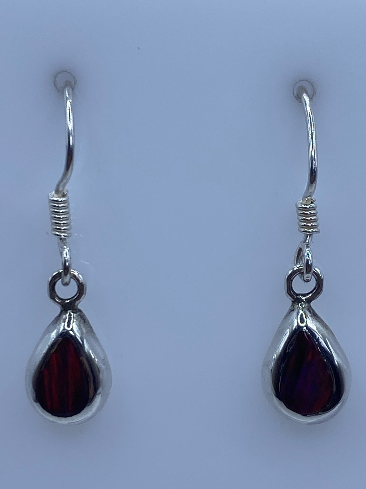 Par de aretes de plata con ópalo de fuego multicolor en forma de gota sobre fondo blanco