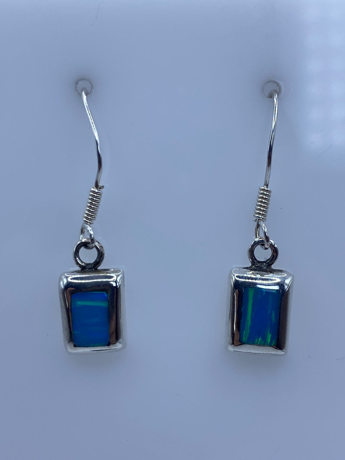 Vista frontal de los aretes colgantes con gancho de plata, piedra azul cielo visible
