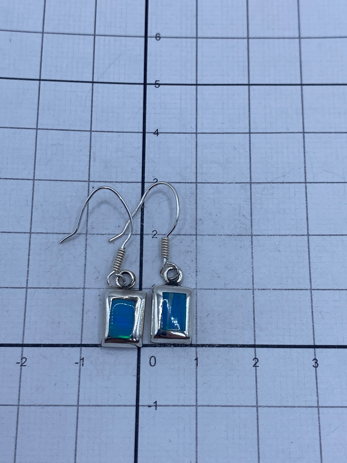 Aretes sobre escala de centímetros mostrando 2.9 cm de largo