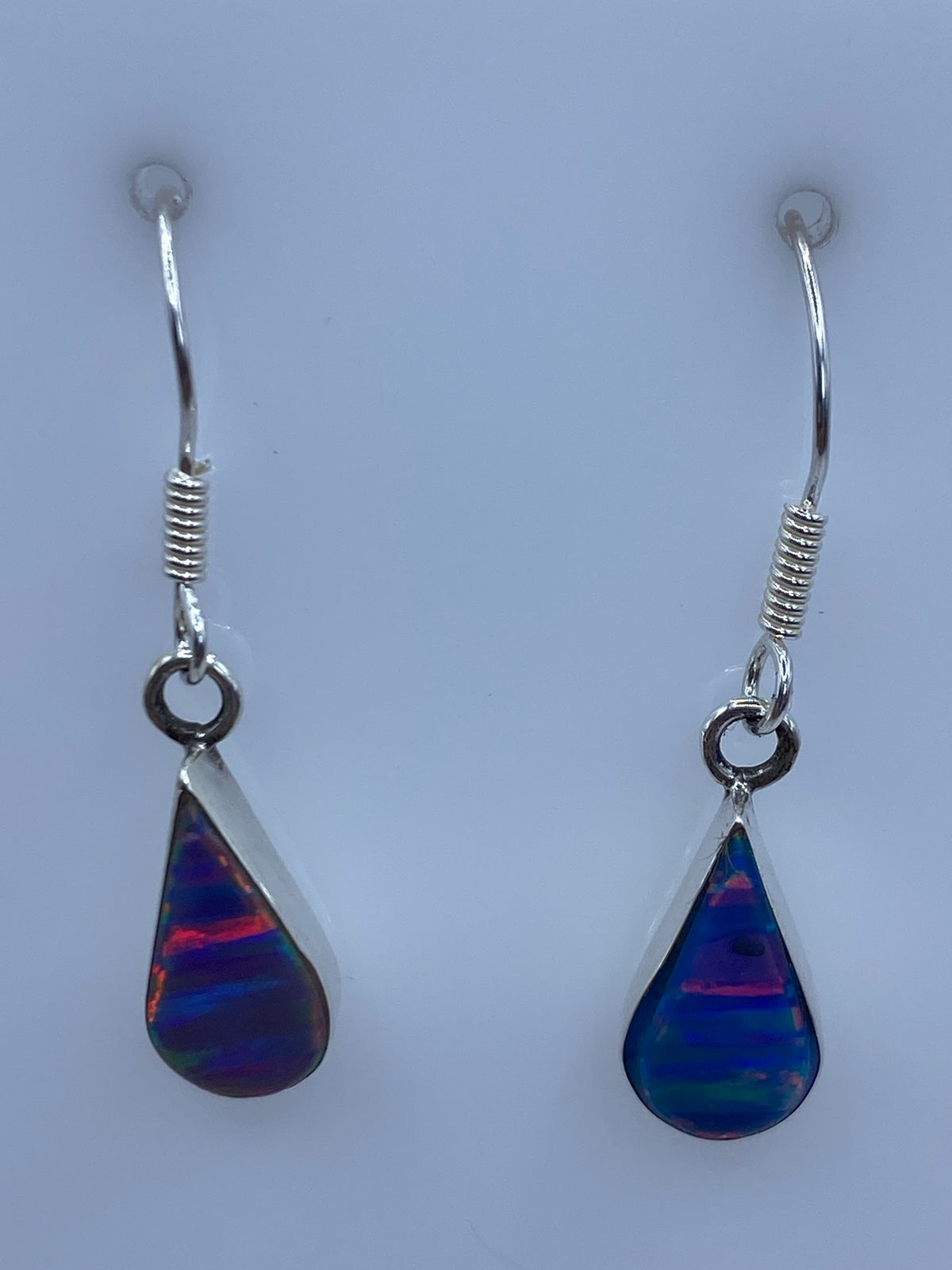 Aretes de ópalo de fuego vistos de frente mostrando la multicoloración y el engaste a mano
