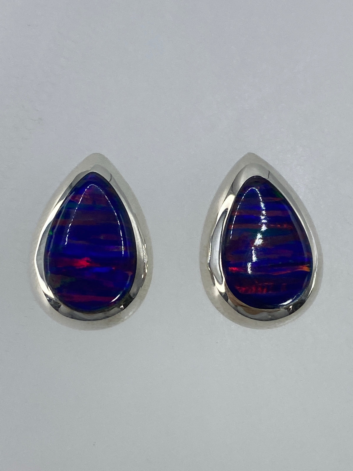 Detalle de un arete mostrando el engaste de plata y el fuego del ópalo