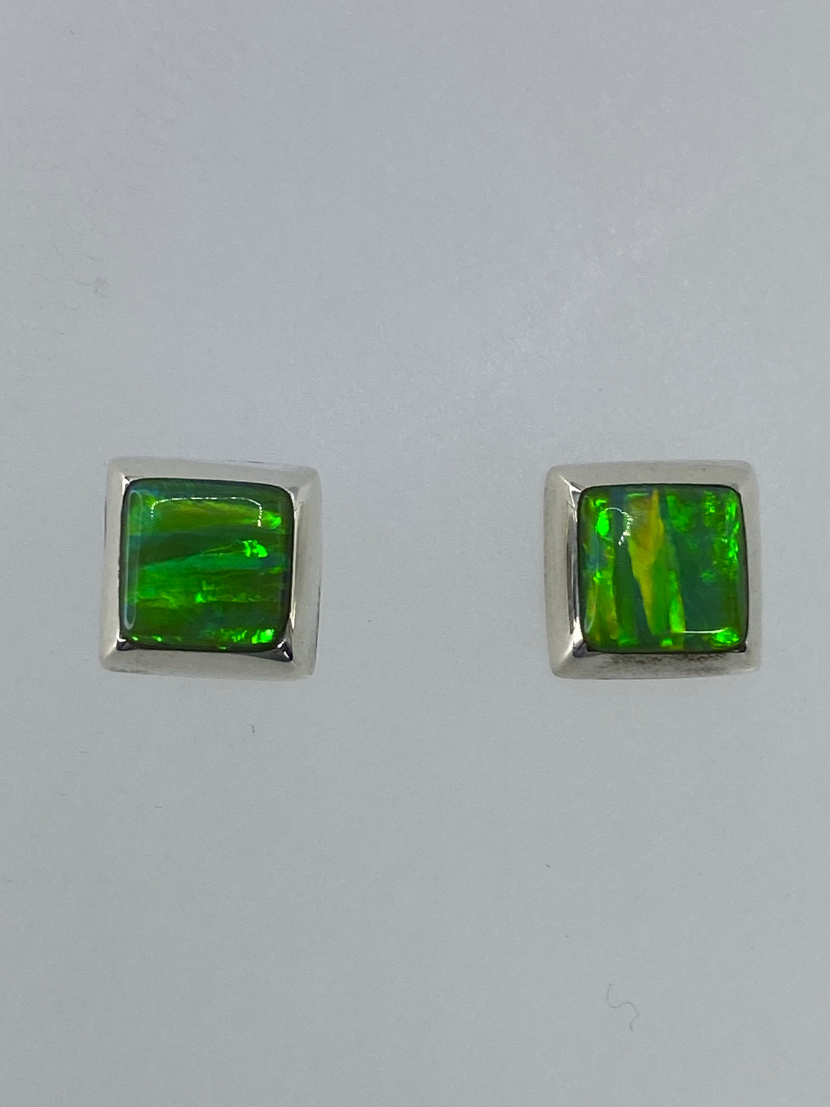 Par de aretes de plata con ópalo de fuego verde limón, vistos de frente