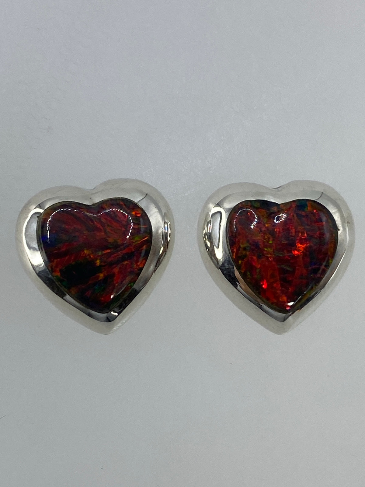 Par de aretes de plata con ópalo de fuego multicolor — vista frontal sobre fondo blanco