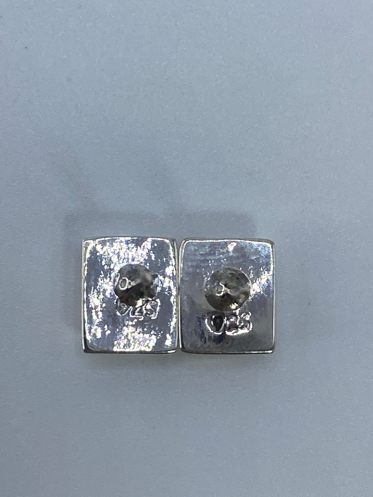 Aretes de plata sobre escala de medida mostrando largo de 1.5 cm