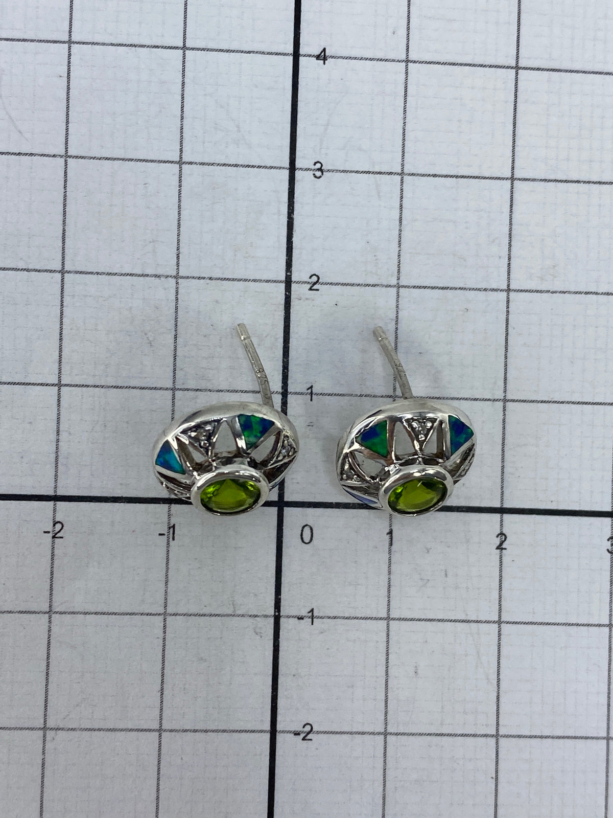 Aretes en la mano mostrando el brillo de la circonia verde olivo y el acabado pulido